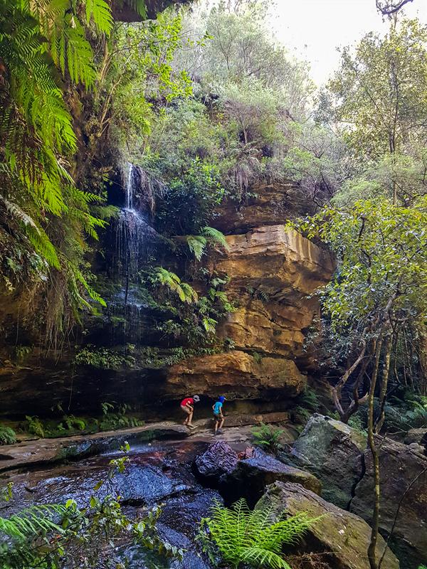 Children walking under the waterfall along Grand Canyon Track